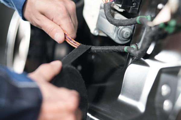 Hands installing 12V vehicle wiring accessory under the hood for off-grid performance