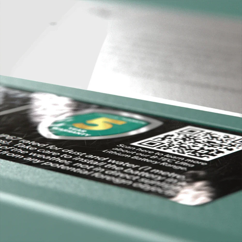 Close-up of a 12V lithium battery label with warranty badge and QR code, Off-Grid 12v accessory.