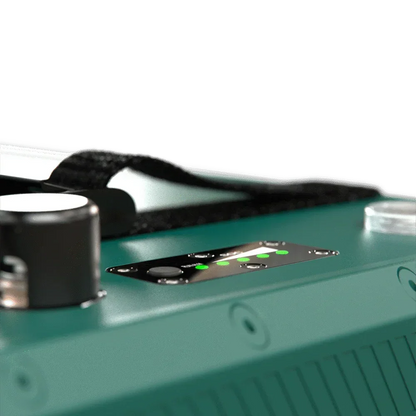 Close-up of a green 12V lithium battery with LED indicator lights and a black carry strap