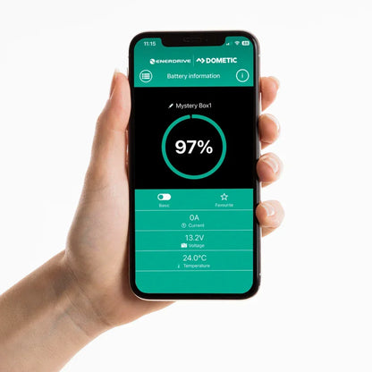 Hand holding smartphone displaying Enerdrive Dometic 12V battery monitor app interface